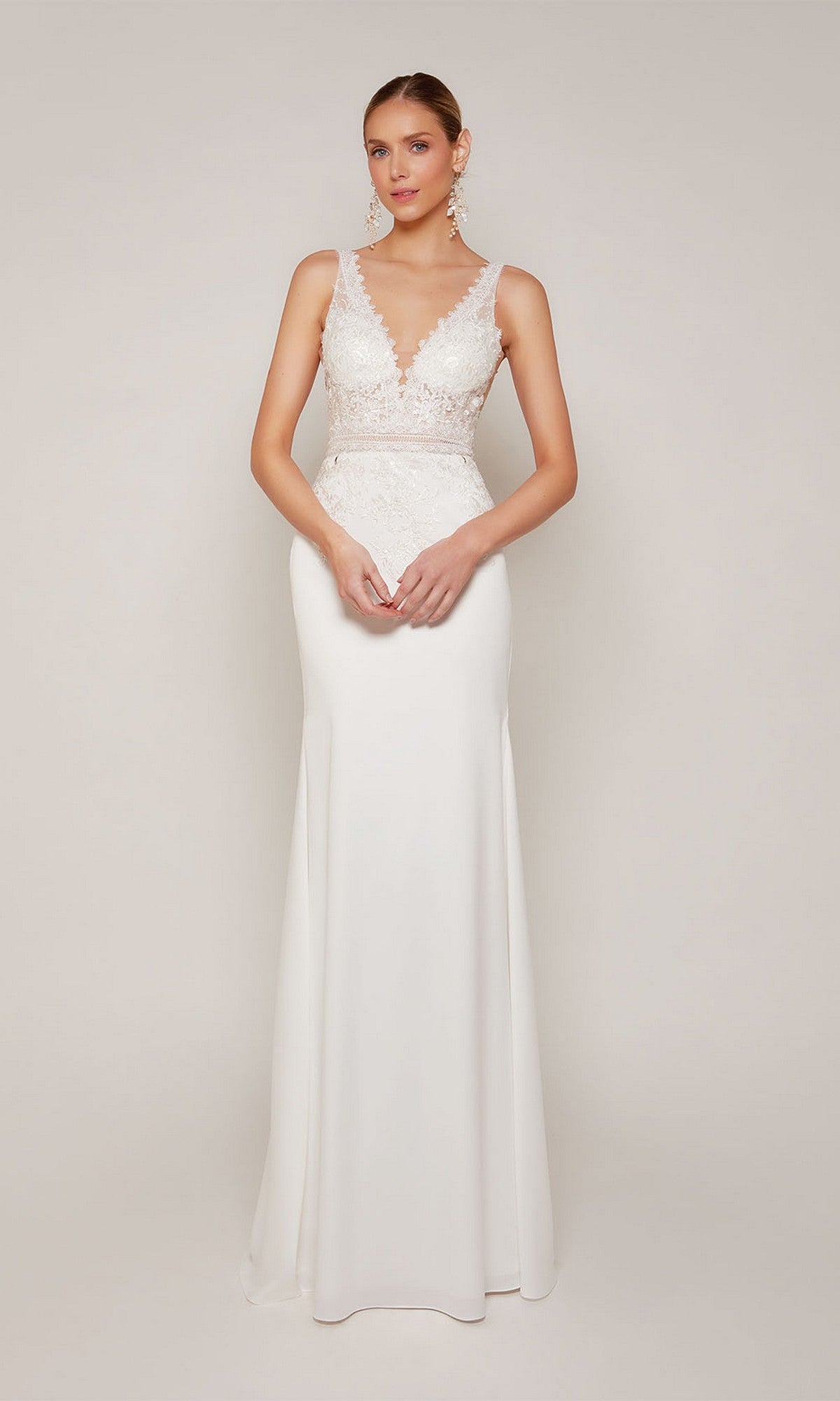 A woman stands against a plain light background wearing the Alyce 7097 long formal dress in diamond white, featuring an illusion lace bodice and a flowing skirt.